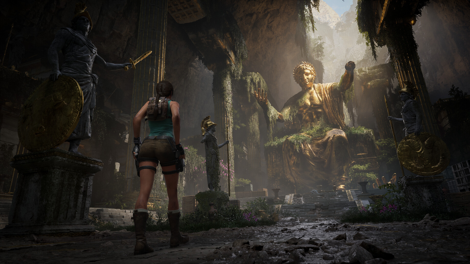 Lara Croft stands before a giant golden statue in a ruined hall in Tomb Raider: Legacy of Atlantis.
